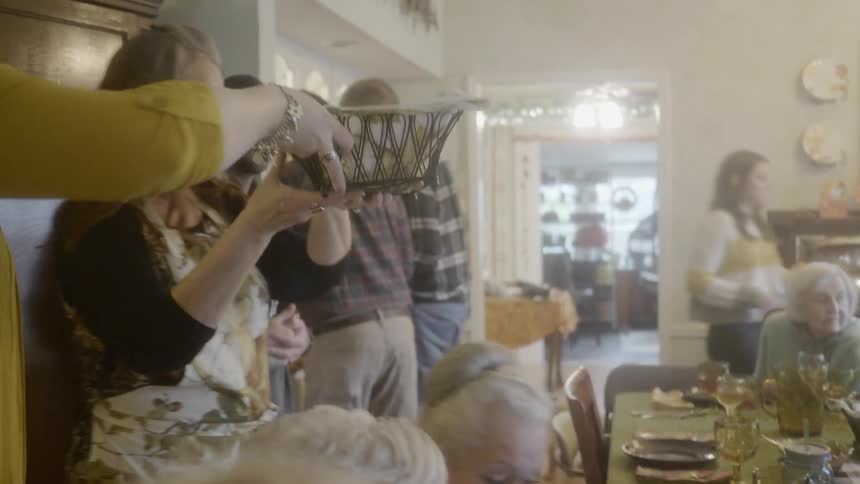 Woman picks up bread basket at dinner party