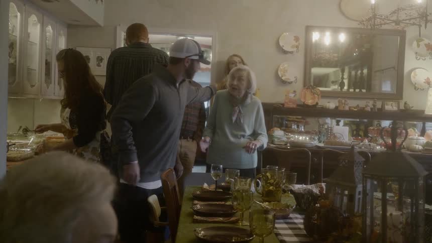 A man greeting and hugging an older woman in a large dining room
