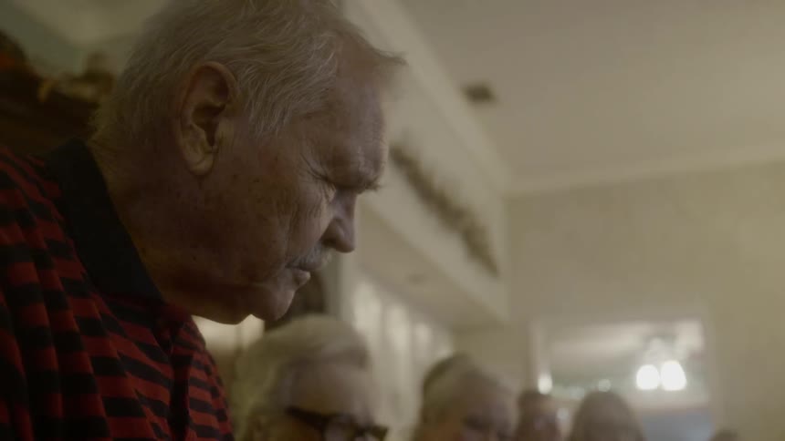 Elderly man speaking to a group of friends