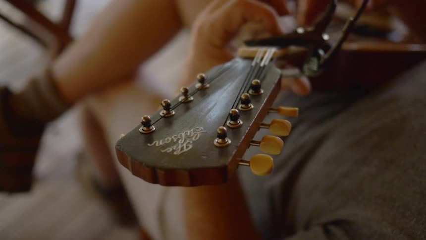 A man leaning back strums his fingers on his guitar strings