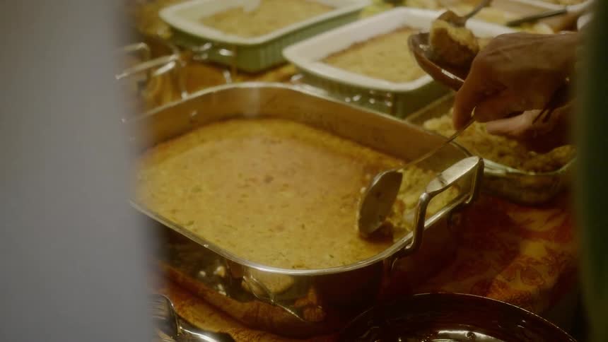 People spoon food out of several different casserole trays