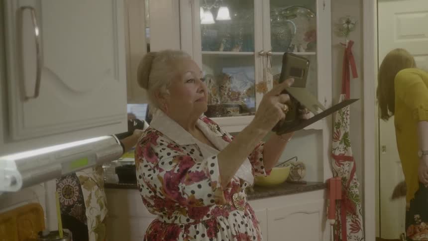 An elderly woman takes a picture with her tablet