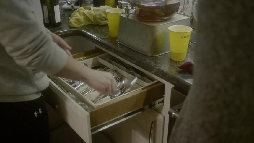 A man sorts silverware and puts them in a drawer