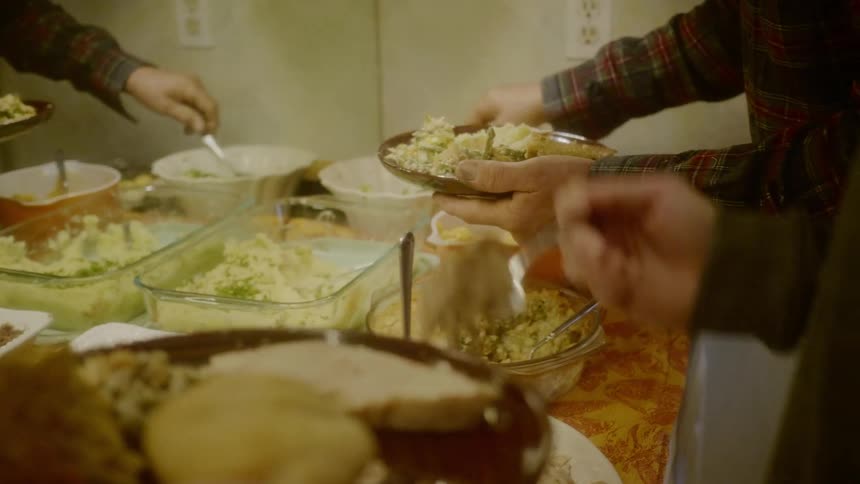People pile food onto their plates from a table array of dishes
