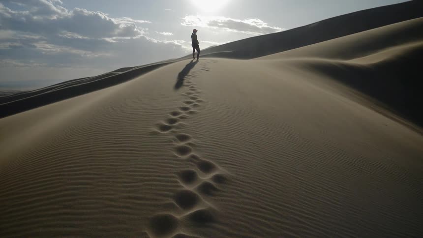 Man walking alone at the desert leaving footprints
