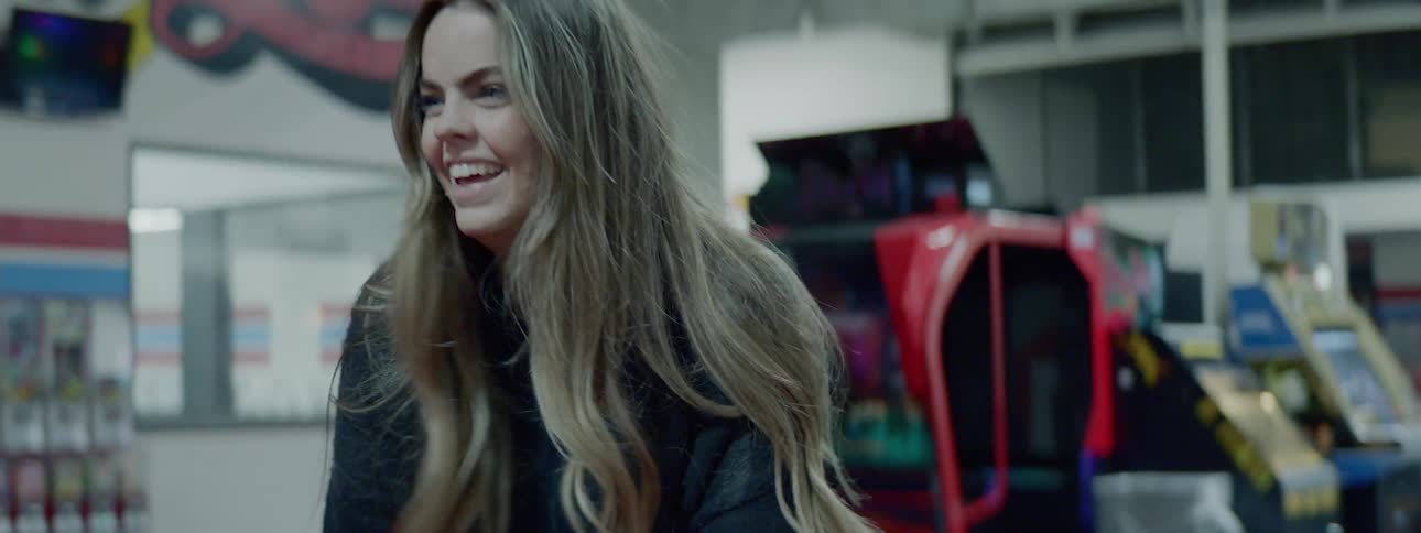 A woman laughs while playing in an arcade