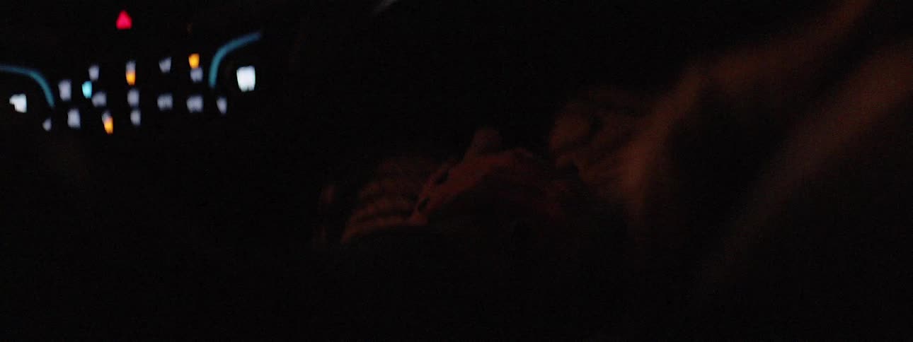 Man and woman hold hands as they ride in vehicle at night