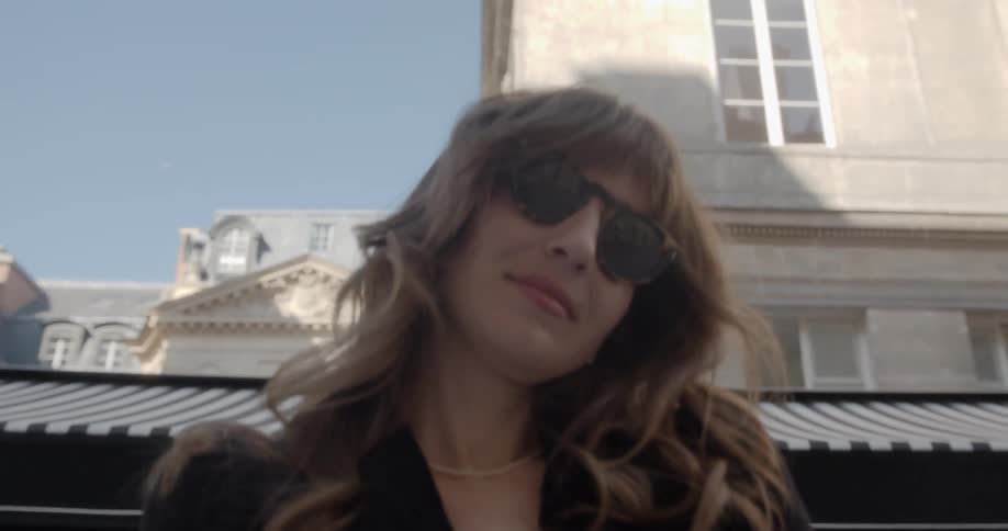 A woman walks out of a shop and poses for the camera