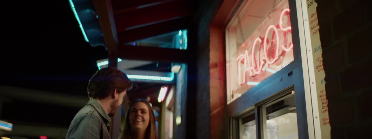 Couple cuddling in front of tacos store
