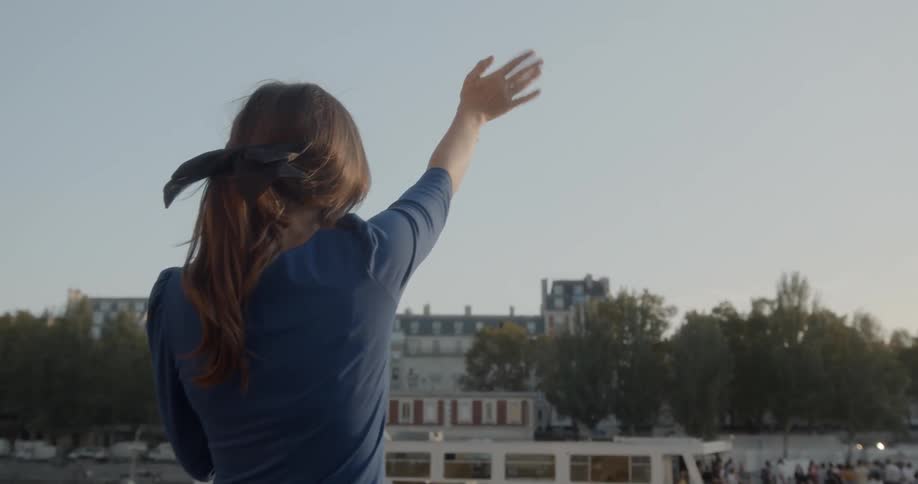Woman waves at passengers on the ferry during daylight