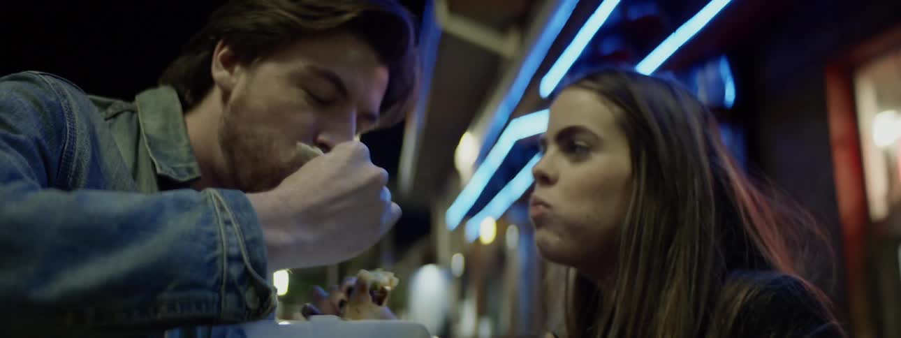 Young couple eating tacos in front of the taco store