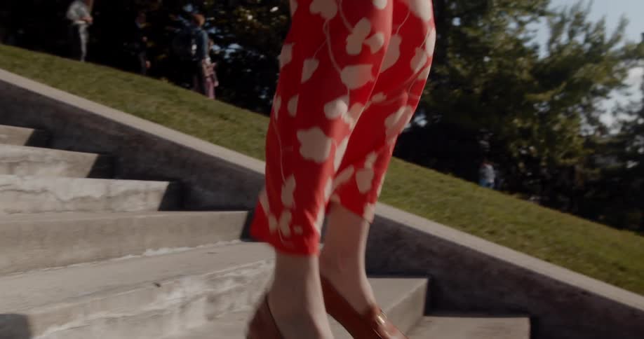 A woman skips and jumps down a staircase outdoors