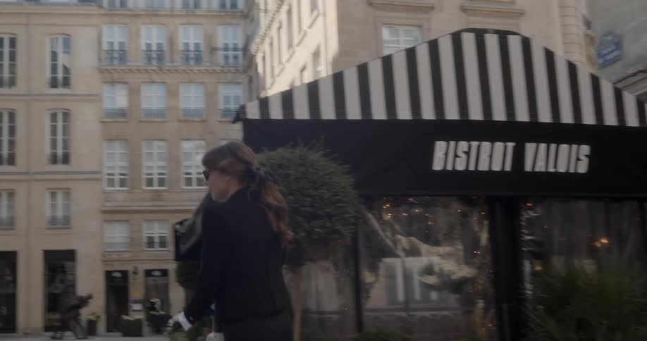 A woman is riding a scooter in an urban plaza area