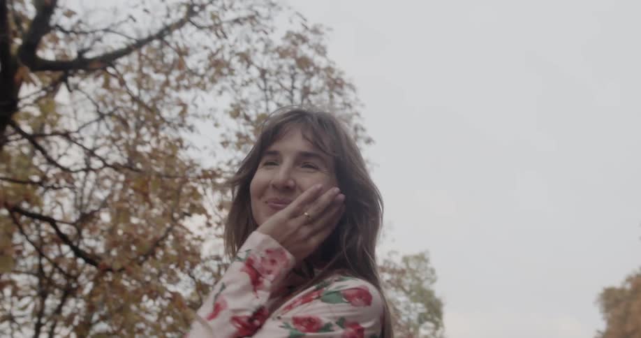 Woman wearing floral patterned shirt walks down and smiles in the public park