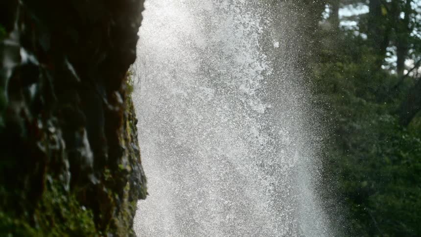 Water droplets fall from a waterfall down a rocky face