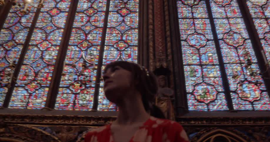 Woman admiring the colorful stained glass windows in a cathedral