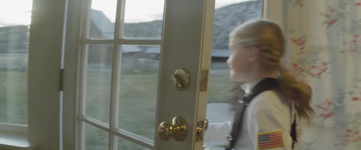 A young girl runs through her house and out the door into the yard