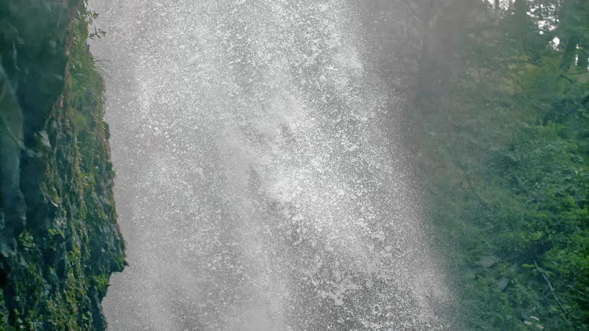 A waterfall creates thousands of different sized drops of water in a forest