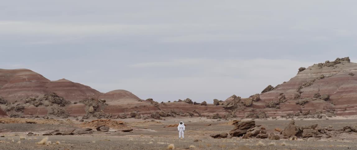 Astronaut standing in middle of crater on a planet
