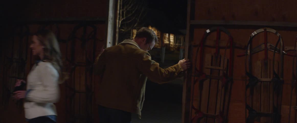A man opens a sliding barn door to let a women in before entering himself