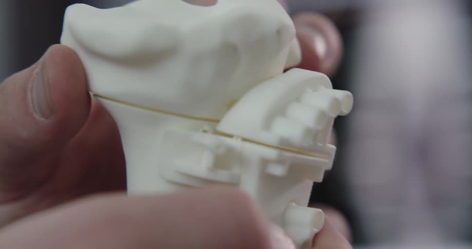 A pair of hands holds a plastic skeleton bone and removes a part