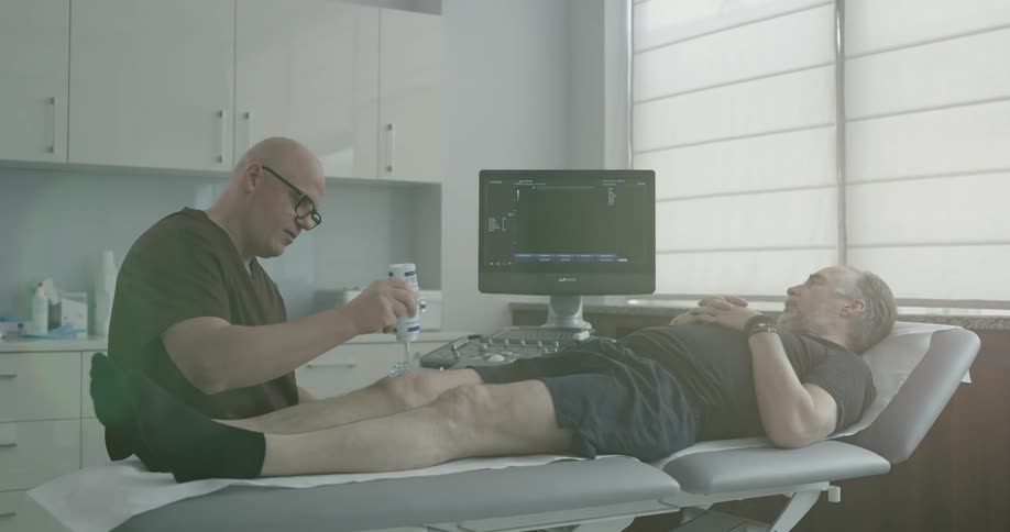 A doctor applies gel to a mans knee before an ultrasound