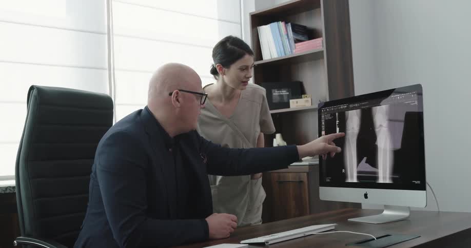 Doctor and nurse study joint on monitor in office