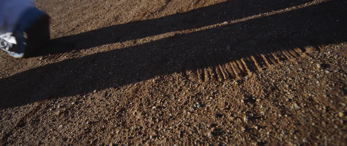 A person in an astronaut suit walks on soil