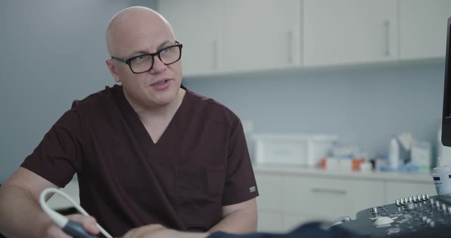 Man in scrubs smooths an ultrasound wand over patients knee