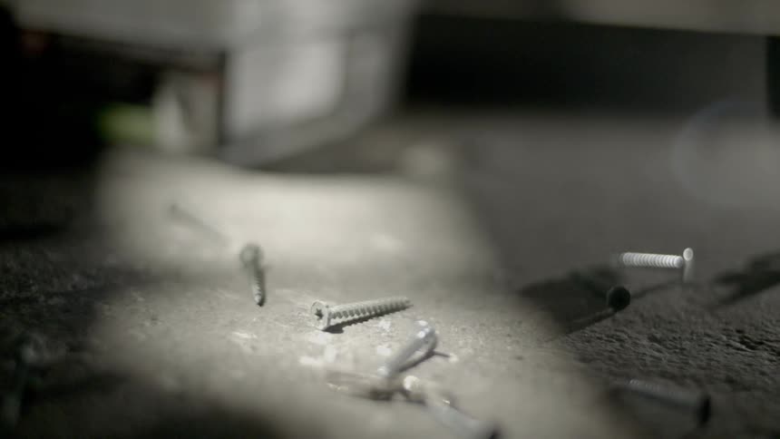 Handful of screws dropping on concrete ground