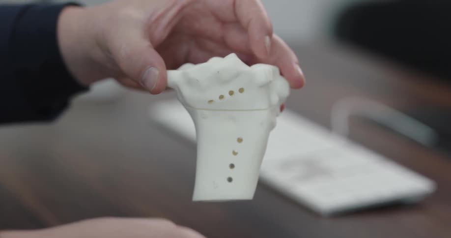 A man holds up pieces of plastic skeleton bones and show how they fit together