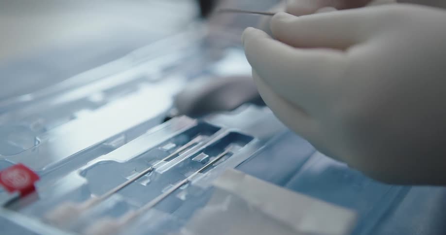 Gloved hands remove pieces of equipment from a tray