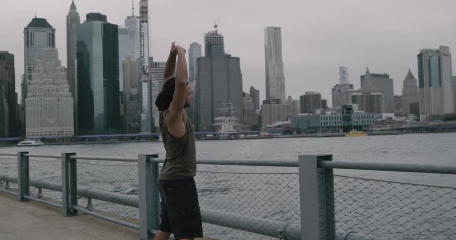 Man jogs to fence and then stretches while starting over water toward downtown