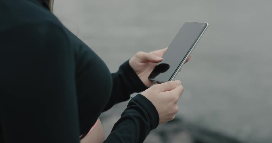 Woman wearing bluetooth earphones uses smartphone in new york city on a cloudy day