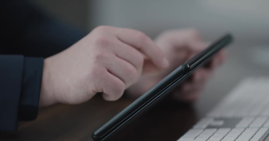 Man sits at the table and uses tablet in the office during daylight
