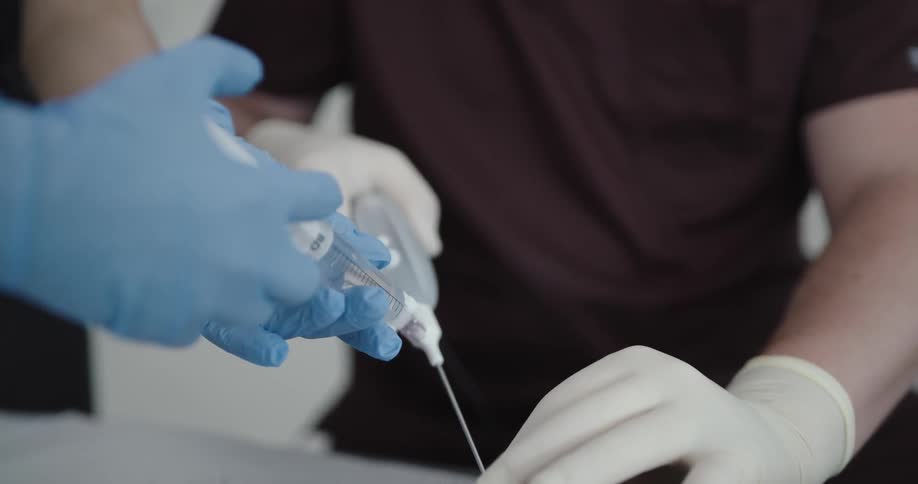 Male and female medical professionals use a syringe