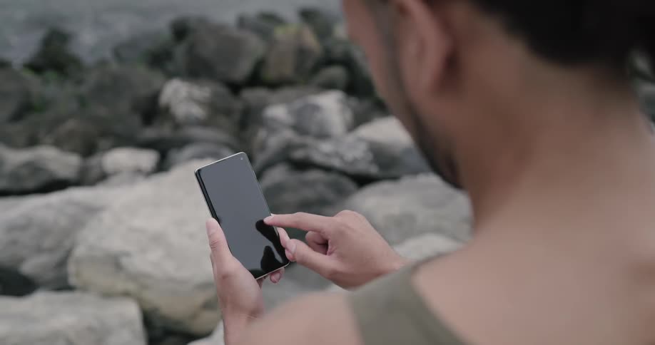 Man playing with phone at the riverbank
