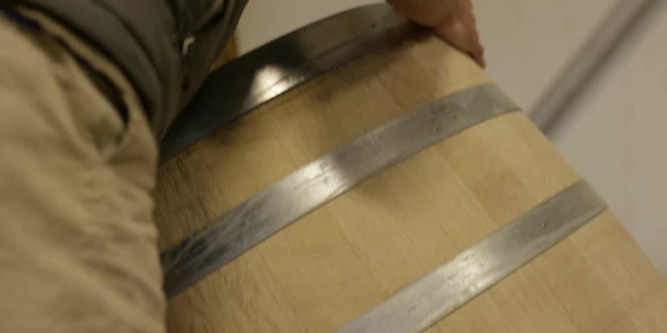 A person is moving large wooden barrels around