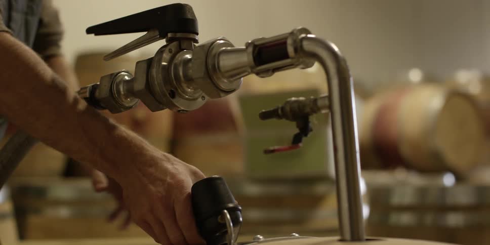 Man in a vest using an instrument on a keg