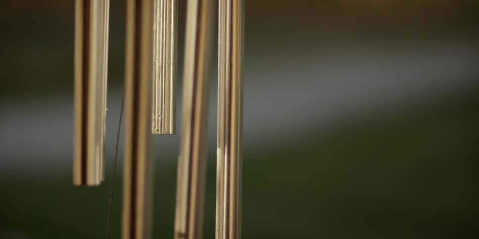 Brass wind chimes seen up close and gently swaying