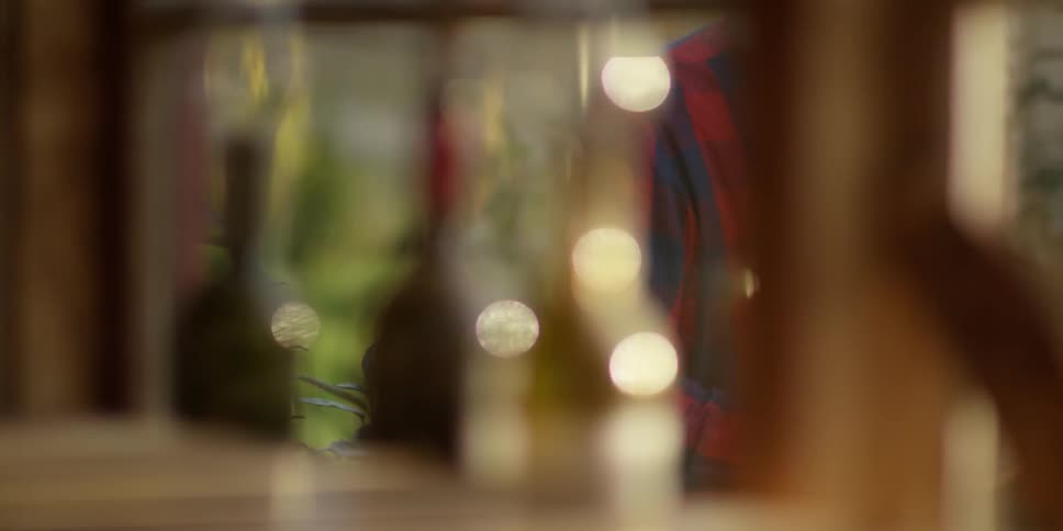 A man walks by wine bottles sitting on a shelf