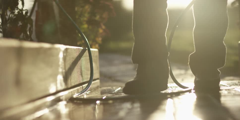 A man's boots get wet while watering plants