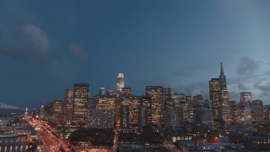 City is brightly lit under a cloudy sky at night