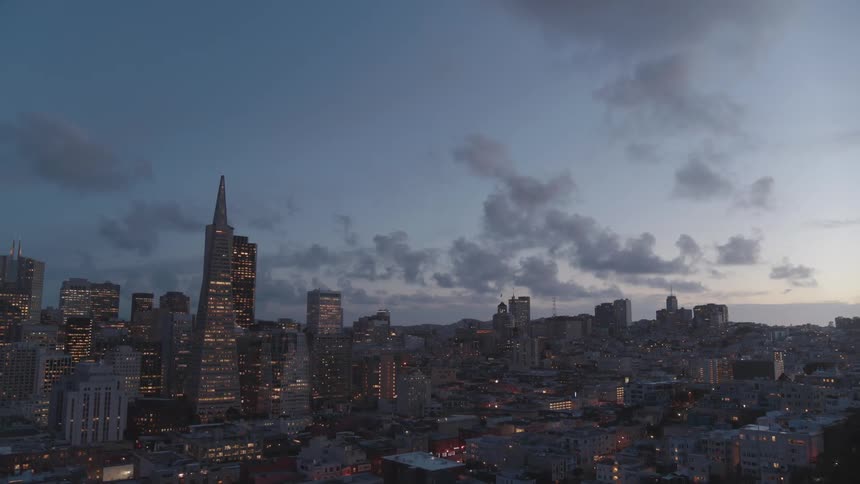 A citys skyline stands against a dusky evening sky
