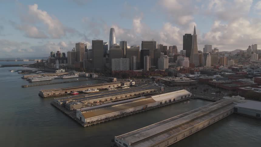 A row of piers is situated along the shore near a downtown city