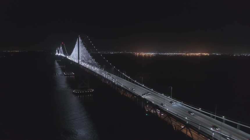 The cars below drive over the bridge at night
