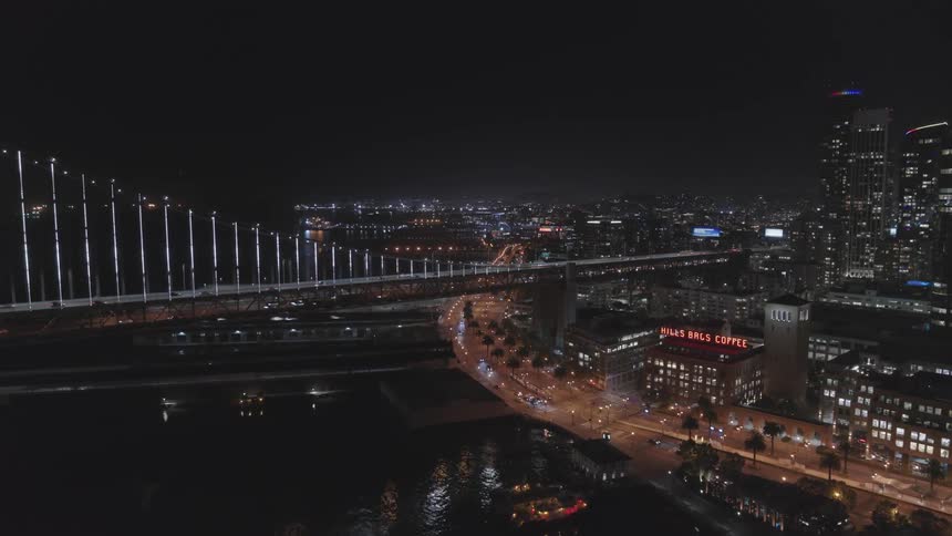 An aerial view of cars driving over a bridge in a downtown city