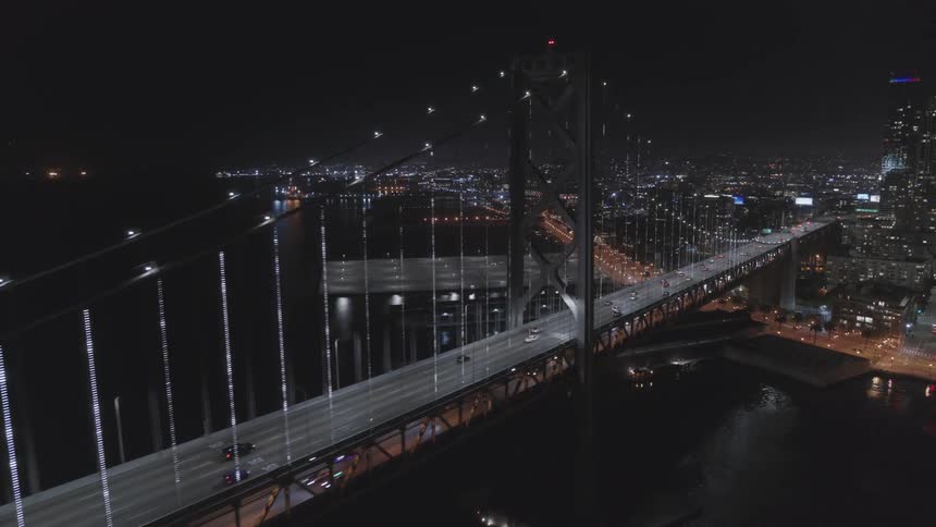 Cars drive across a bridge towards a metropolis