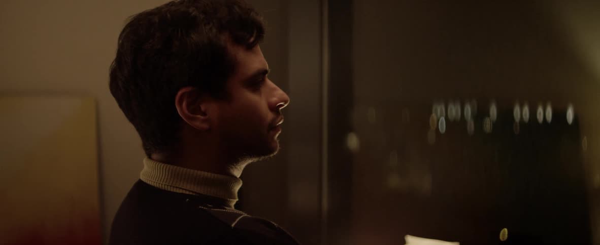 Dark haired man with high white collar is looking at something in front of him