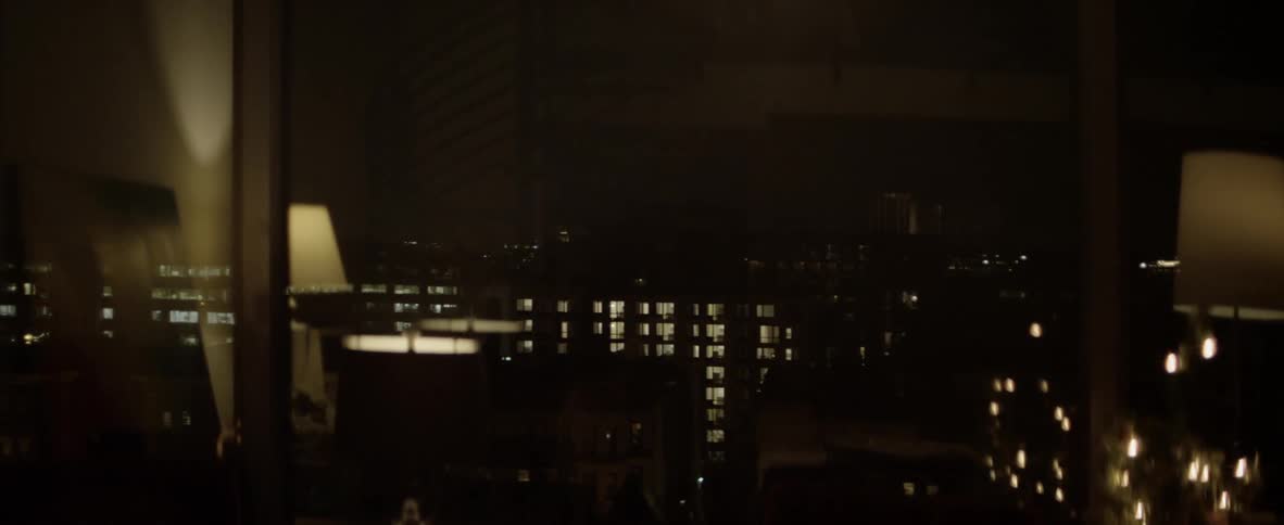Lit windows of other buildings seen through glossy window at night